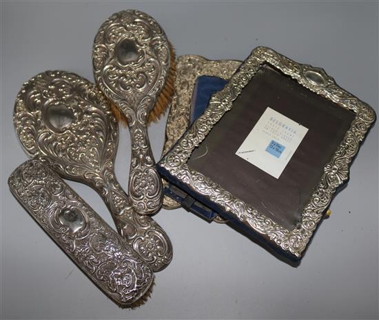 An Edwardian silver mounted photograph frame, a plated frame, two silver mounted brushes and a mirror.